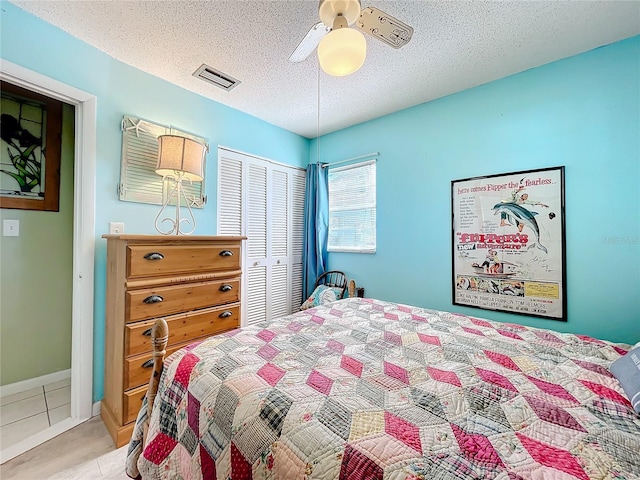 tiled bedroom with a closet, ceiling fan, and a textured ceiling