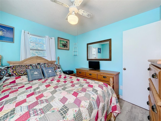 bedroom with light hardwood / wood-style flooring, ceiling fan, and a textured ceiling