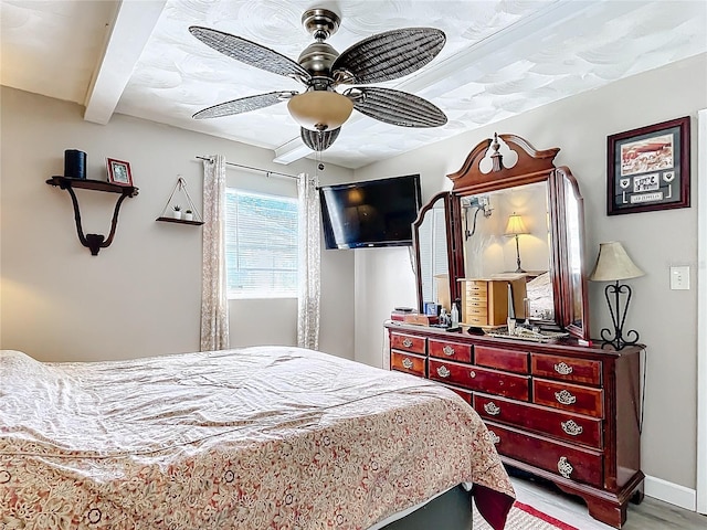 bedroom with ceiling fan, beamed ceiling, and light hardwood / wood-style floors