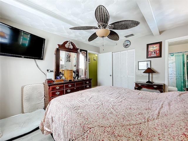 bedroom with ceiling fan, beamed ceiling, a closet, and ensuite bathroom