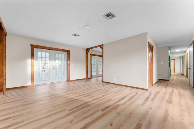 spare room with light wood-style floors, baseboards, visible vents, and french doors