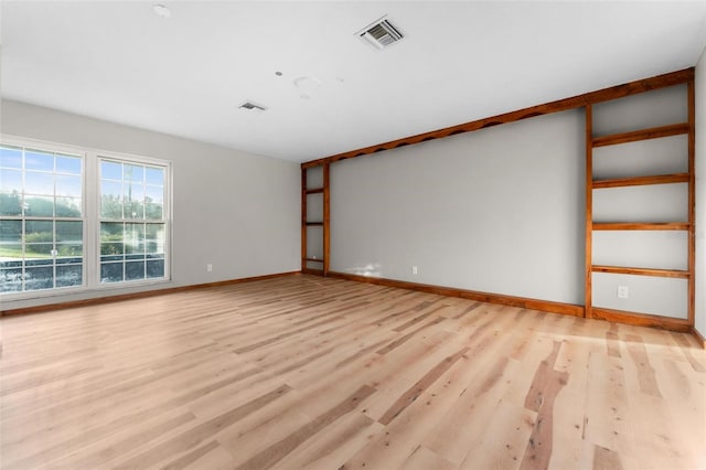 spare room featuring light wood-style flooring, visible vents, and baseboards