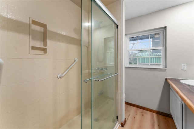 full bathroom with a stall shower, wood finished floors, and vanity