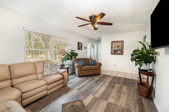 living room featuring ceiling fan, a textured ceiling, baseboards, and wood finished floors