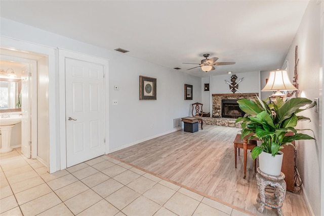 living area featuring a ceiling fan, visible vents, a fireplace, and light wood finished floors