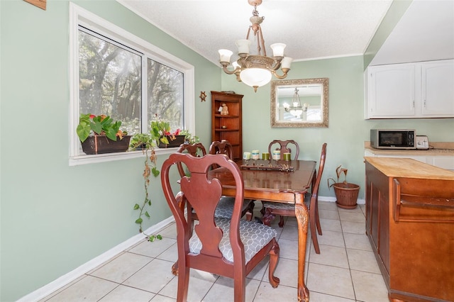 dining area with crown molding, a notable chandelier, light tile patterned flooring, a textured ceiling, and baseboards