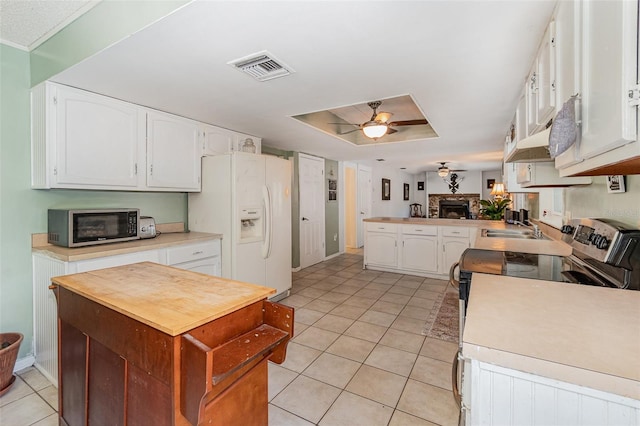 kitchen featuring stainless steel electric stove, visible vents, ceiling fan, a sink, and white fridge with ice dispenser