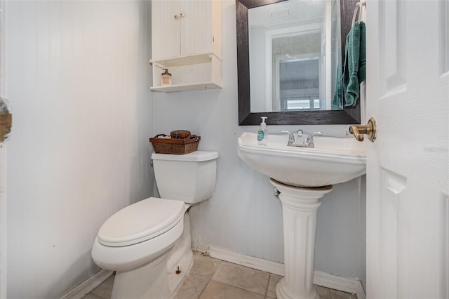 half bath with baseboards, toilet, and tile patterned floors