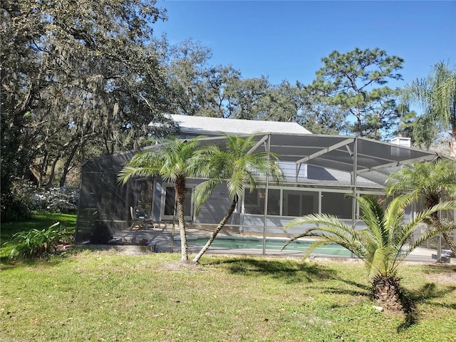 rear view of property with a lanai, an outdoor pool, and a yard