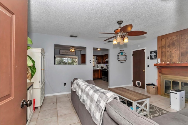 tiled living room with ceiling fan and a textured ceiling