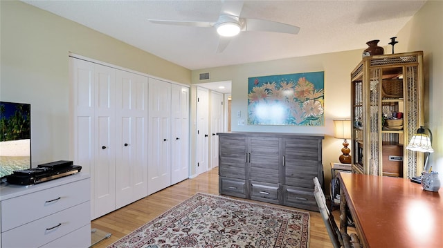 bedroom featuring ceiling fan, light hardwood / wood-style floors, a closet, and a textured ceiling