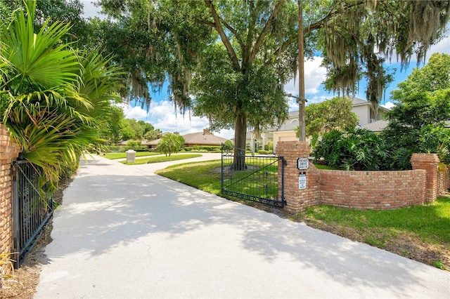 surrounding community featuring driveway, a lawn, a gate, and a fenced front yard