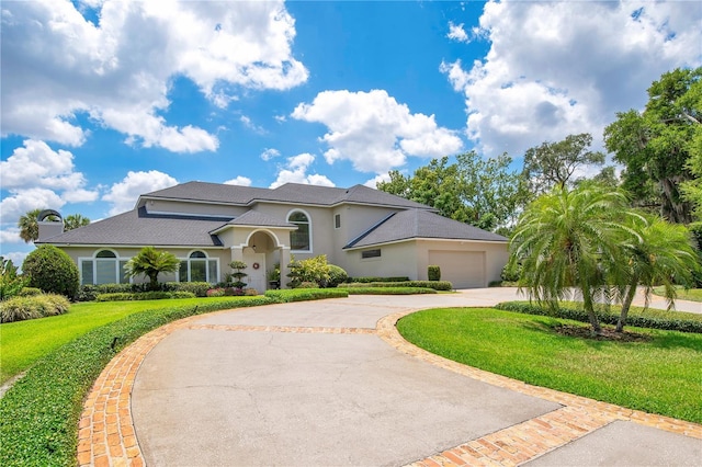 mediterranean / spanish house with a garage, driveway, a front yard, and stucco siding