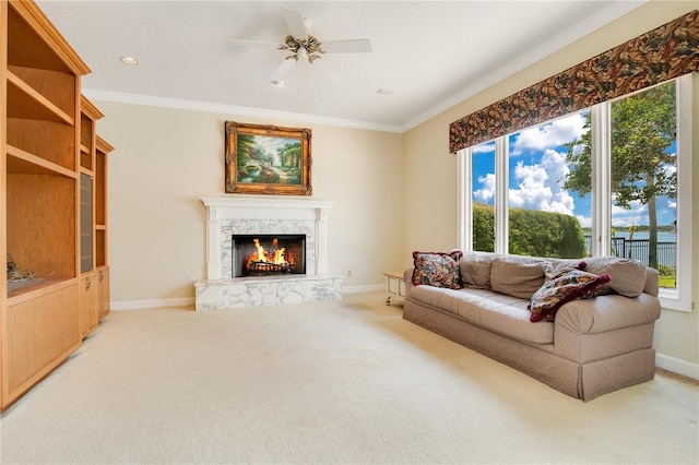 carpeted living area featuring ceiling fan, crown molding, baseboards, and a premium fireplace