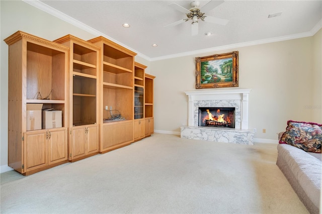 living room with ceiling fan, light colored carpet, a high end fireplace, baseboards, and crown molding