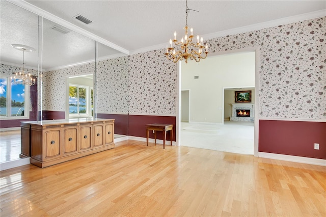 interior space with wallpapered walls, visible vents, wainscoting, an inviting chandelier, and crown molding