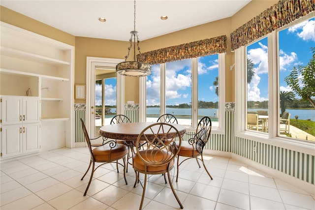 dining area with built in features, recessed lighting, a water view, and light tile patterned floors