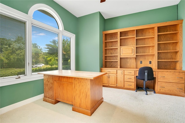 office area featuring light colored carpet, built in desk, and baseboards