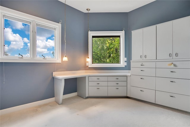 interior space with light colored carpet, built in desk, and baseboards