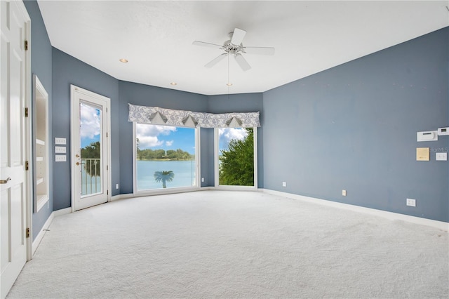 unfurnished room with a ceiling fan, light colored carpet, and baseboards