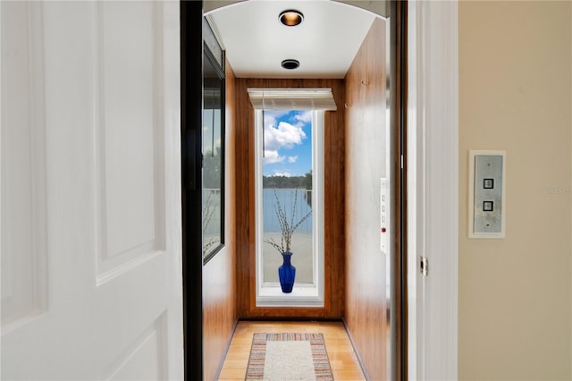 doorway featuring arched walkways, elevator, and light wood-style flooring