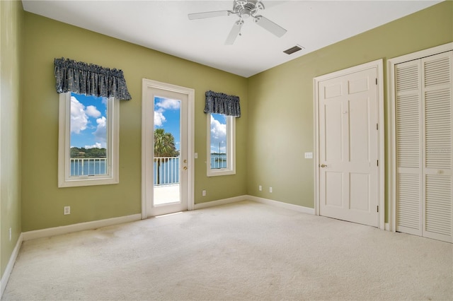 unfurnished bedroom with light carpet, access to outside, visible vents, and baseboards