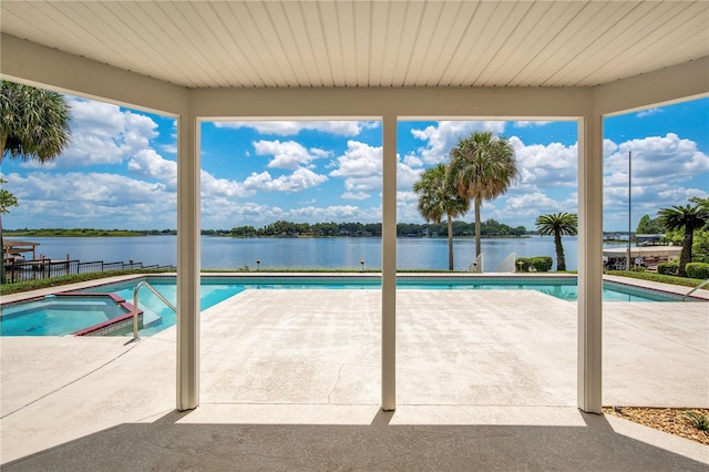 view of pool featuring a patio area, a water view, fence, and a pool with connected hot tub