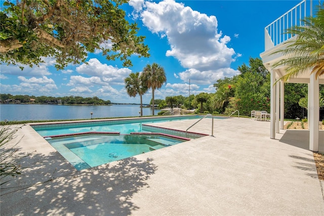 pool featuring a water view, a patio, and an in ground hot tub