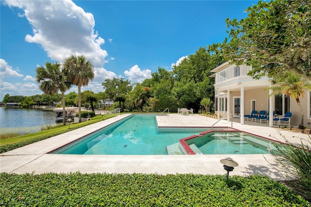 view of pool featuring a patio, a water view, and a pool with connected hot tub