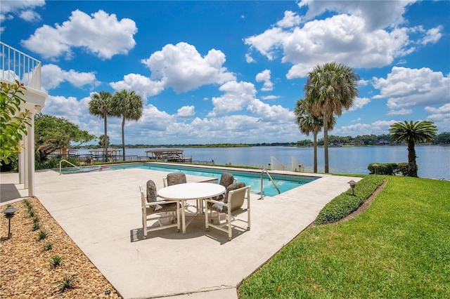 community pool featuring a patio area, a water view, and a lawn