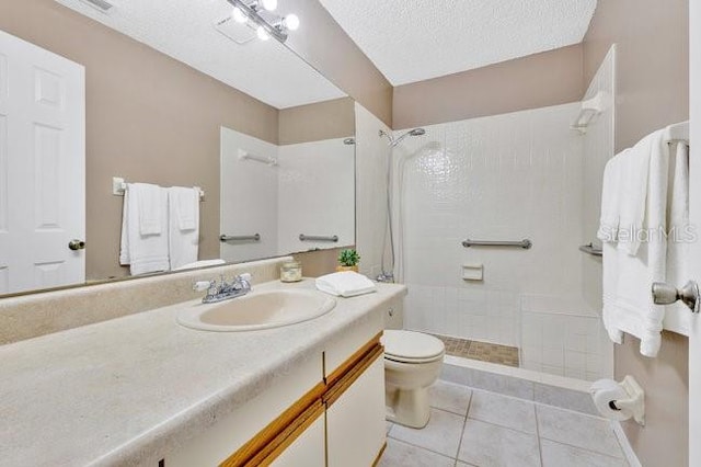 bathroom with toilet, tile patterned flooring, a tile shower, and vanity