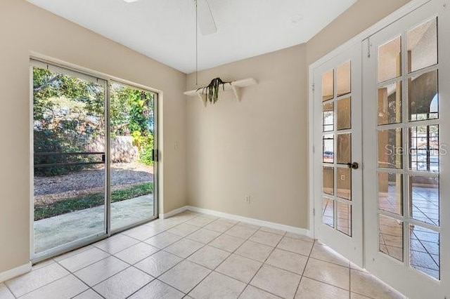 spare room with ceiling fan, light tile patterned flooring, and baseboards