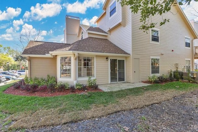 back of house featuring a patio area, a lawn, a chimney, and central air condition unit