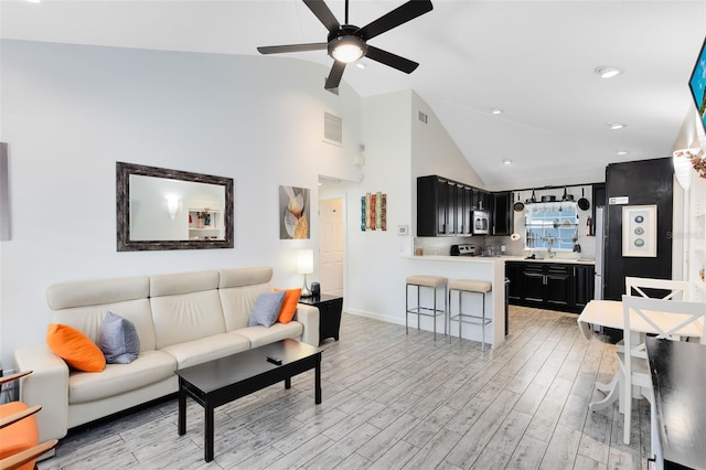 living room with light hardwood / wood-style floors, high vaulted ceiling, and ceiling fan