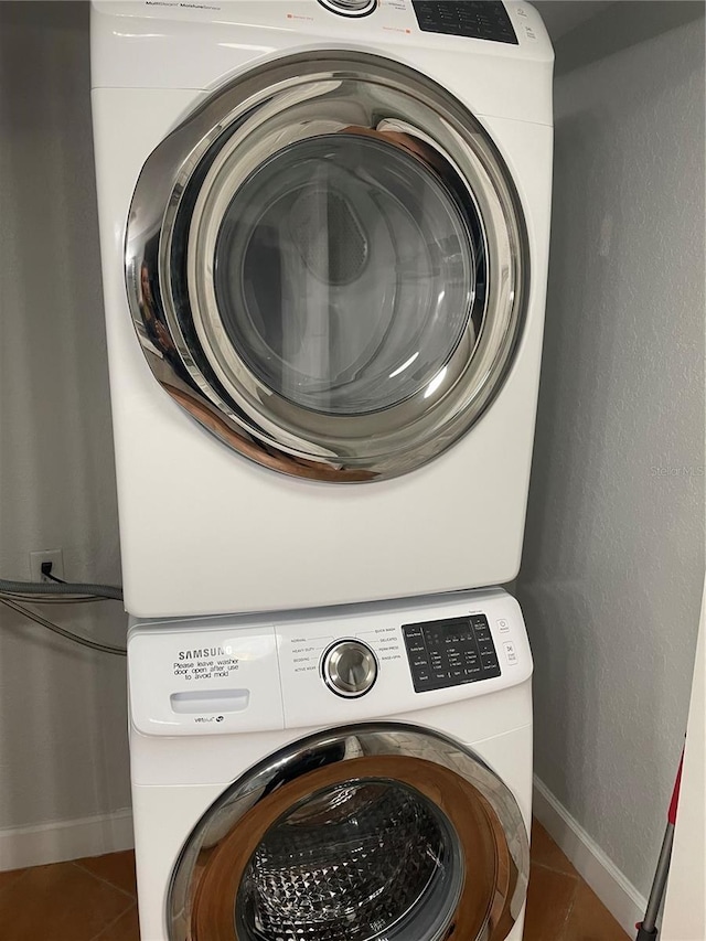 laundry area with stacked washer / drying machine and tile patterned floors