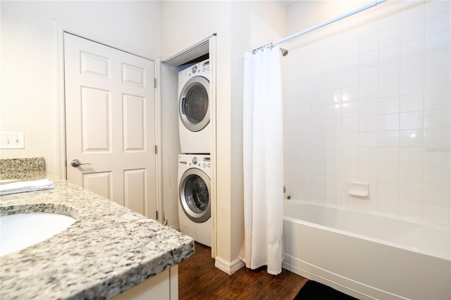 bathroom featuring hardwood / wood-style flooring, stacked washer / dryer, shower / bath combination with curtain, and vanity