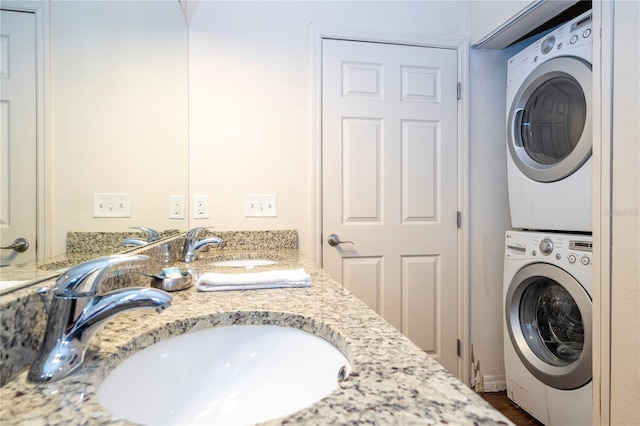 clothes washing area with stacked washer / drying machine and sink