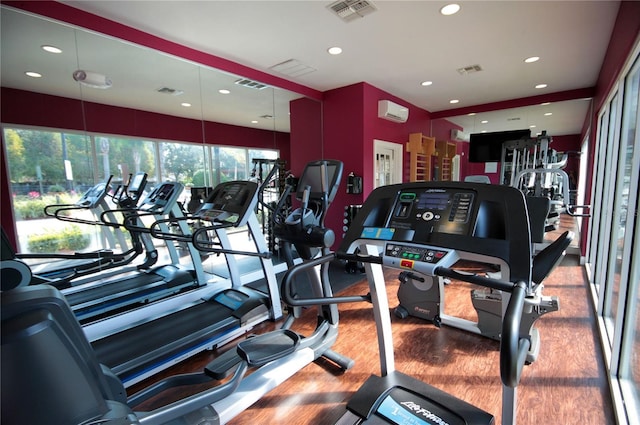 exercise room with hardwood / wood-style flooring and a wall mounted air conditioner