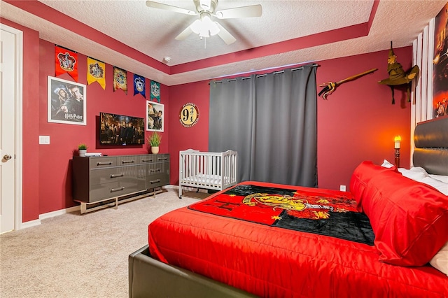 bedroom featuring a textured ceiling, carpet floors, and a tray ceiling