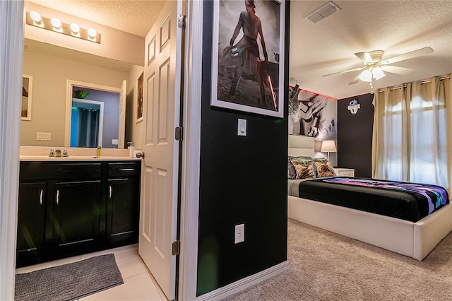 bedroom featuring ensuite bath, a textured ceiling, ceiling fan, light carpet, and sink