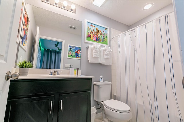 bathroom with a textured ceiling, toilet, vanity, and a shower with curtain