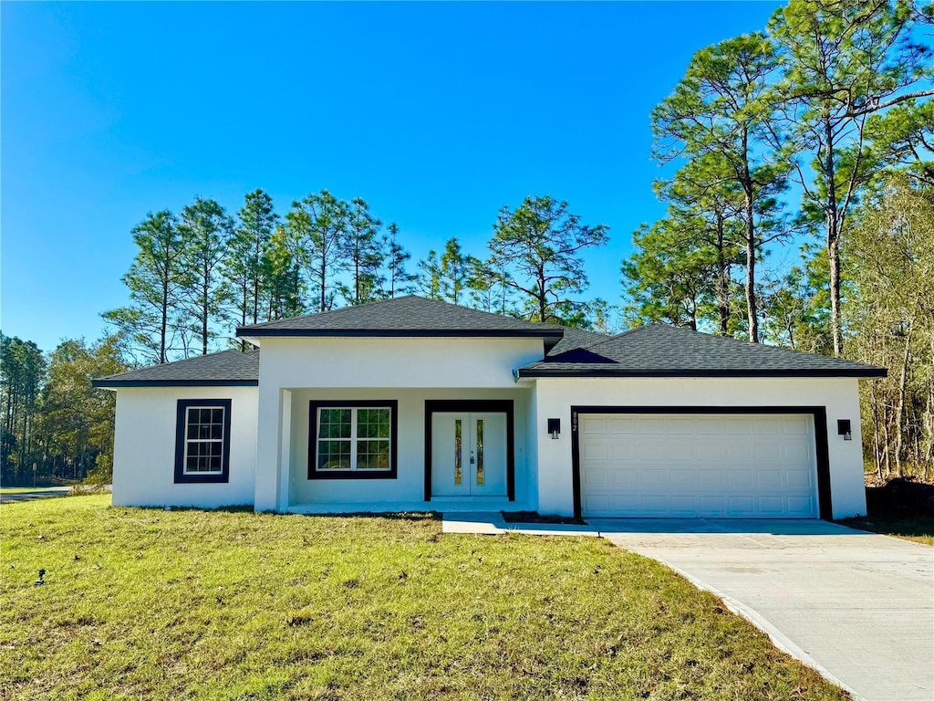 view of front of house with a garage, concrete driveway, french doors, stucco siding, and a front yard