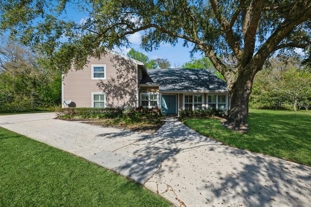 tri-level home with concrete driveway and a front lawn