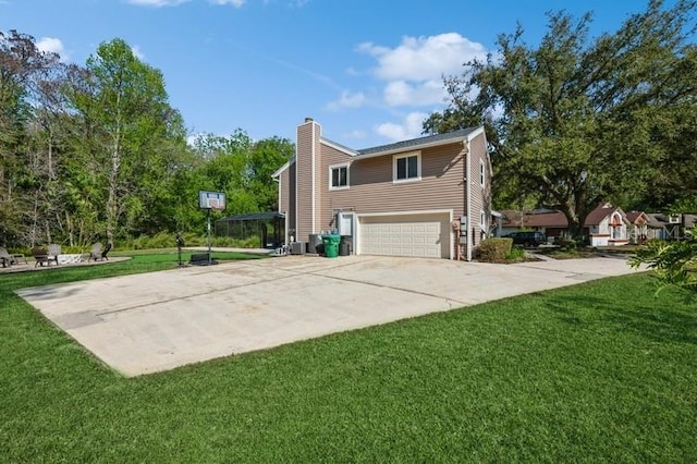 view of side of property with concrete driveway, a yard, a chimney, and an attached garage