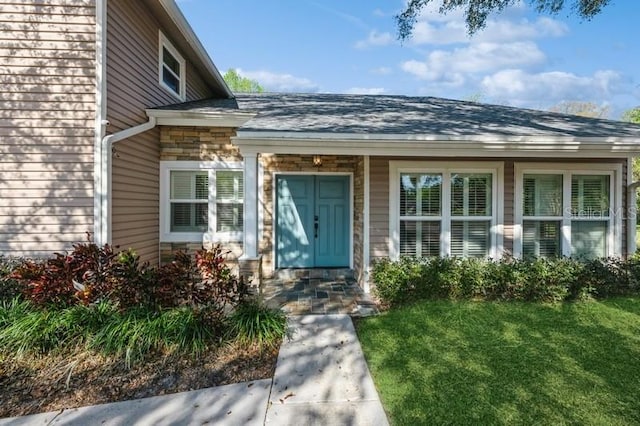 doorway to property featuring stone siding and a yard