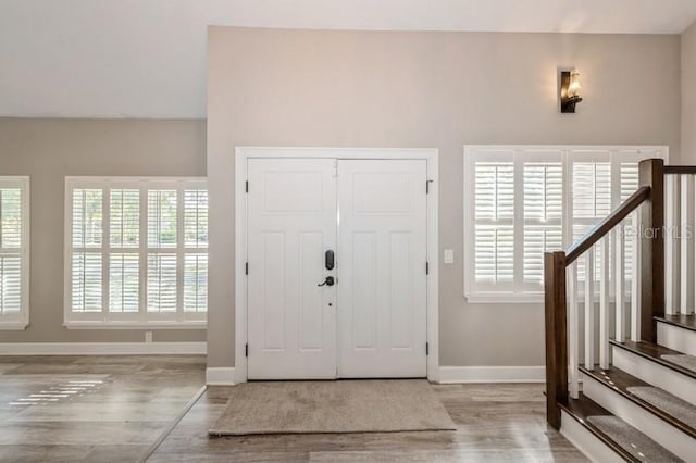 entrance foyer with stairway, wood finished floors, and baseboards