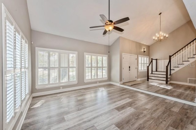 foyer entrance with stairs, wood finished floors, high vaulted ceiling, baseboards, and ceiling fan with notable chandelier