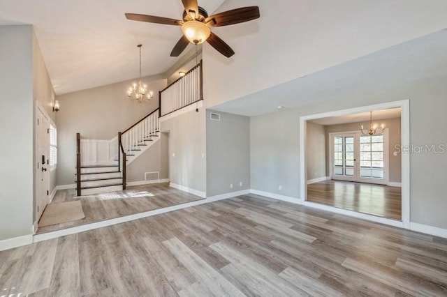 unfurnished living room with visible vents, a high ceiling, wood finished floors, baseboards, and stairs