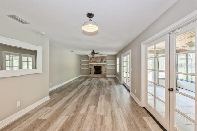 unfurnished living room featuring light wood-type flooring, visible vents, a fireplace, and baseboards