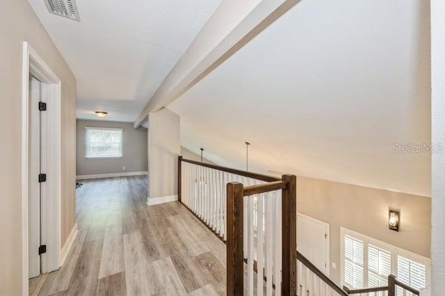 hall with baseboards, visible vents, vaulted ceiling, and light wood finished floors